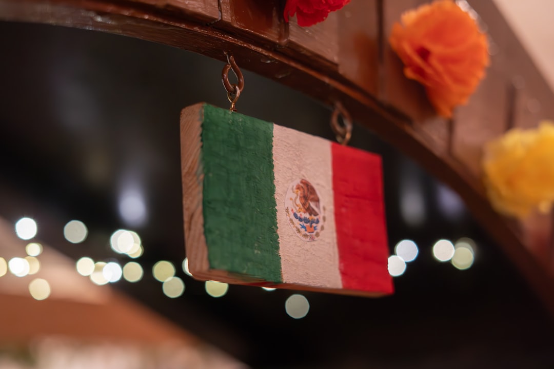 A small wooden mexican flag hangs with bokeh lights.