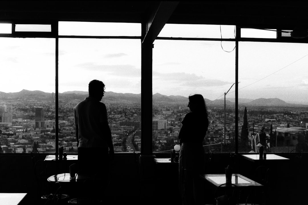 A couple of people standing in front of a window