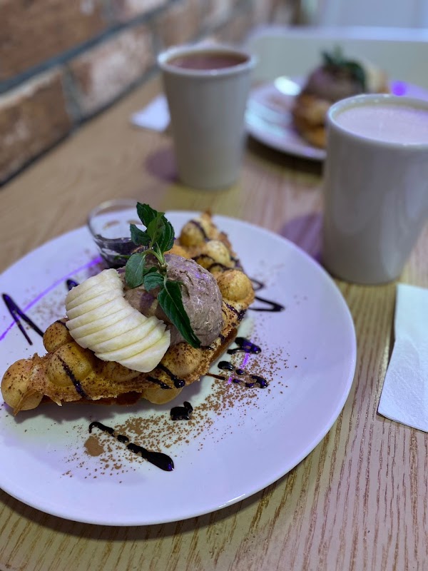 Haru By Day Café pet‑friendly patio, showing bubble waffles topped with hazelnuts and a steaming herbal tea