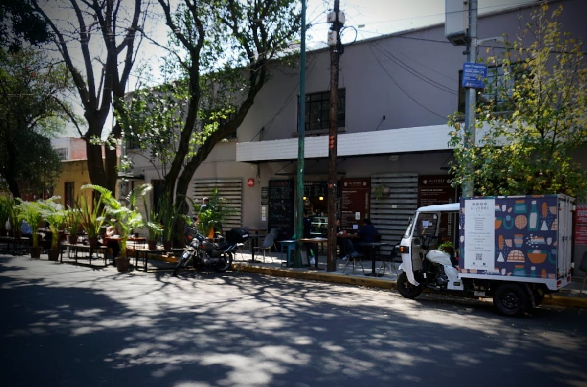 Café al aire libre en Alverre Bistro, un bistró con mesas de madera y comensales disfrutando de platos gourmet