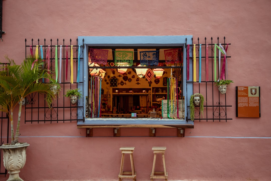 a pink building with a blue window and two wooden stools