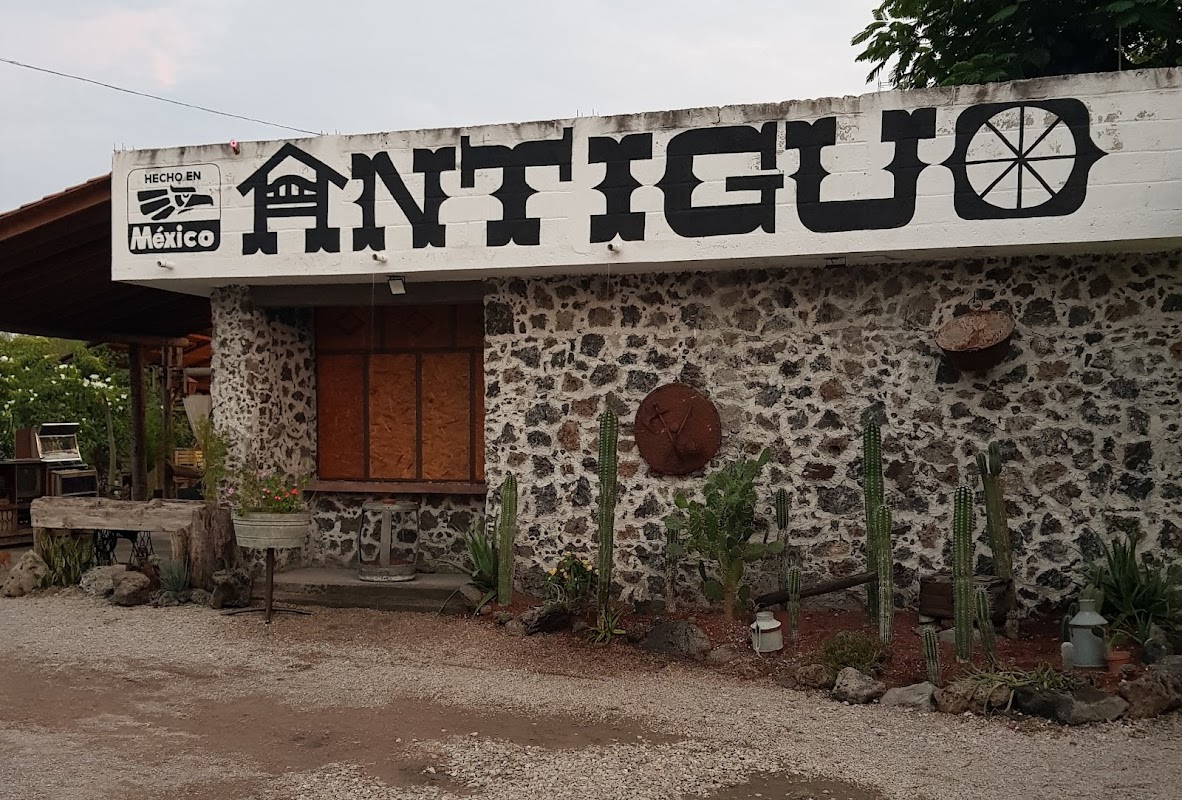 Exterior de Restaurante Antiguo con su letrero de madera y escenario donde suena música en vivo, mostrando un plato de pibil de cerdo