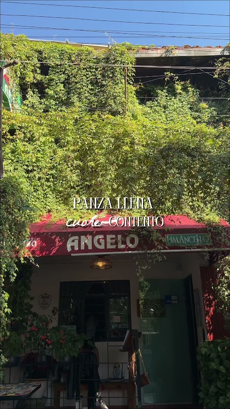 Exterior iluminado de Ristorante Angelo con mesas en la calle y una botella de vino tinto sobre la mesa