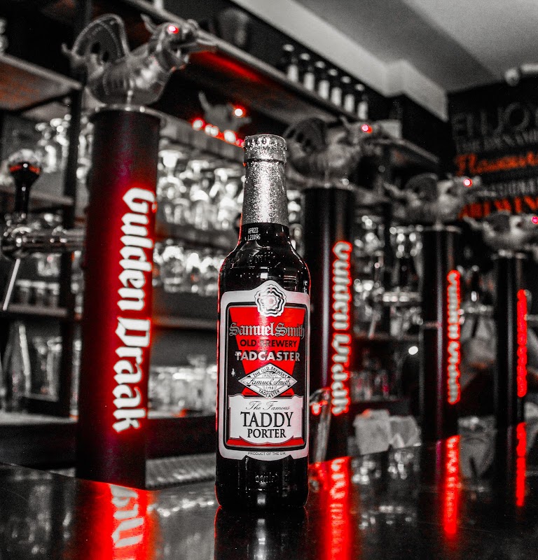 Fachada de Gulden Draak con letrero de neón azul iluminado, vista nocturna de la calle Pedro Moreno