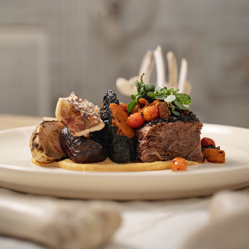 Plato de short ribs y una copa de tequila en Hueso Restaurante — enfoque en la mesa