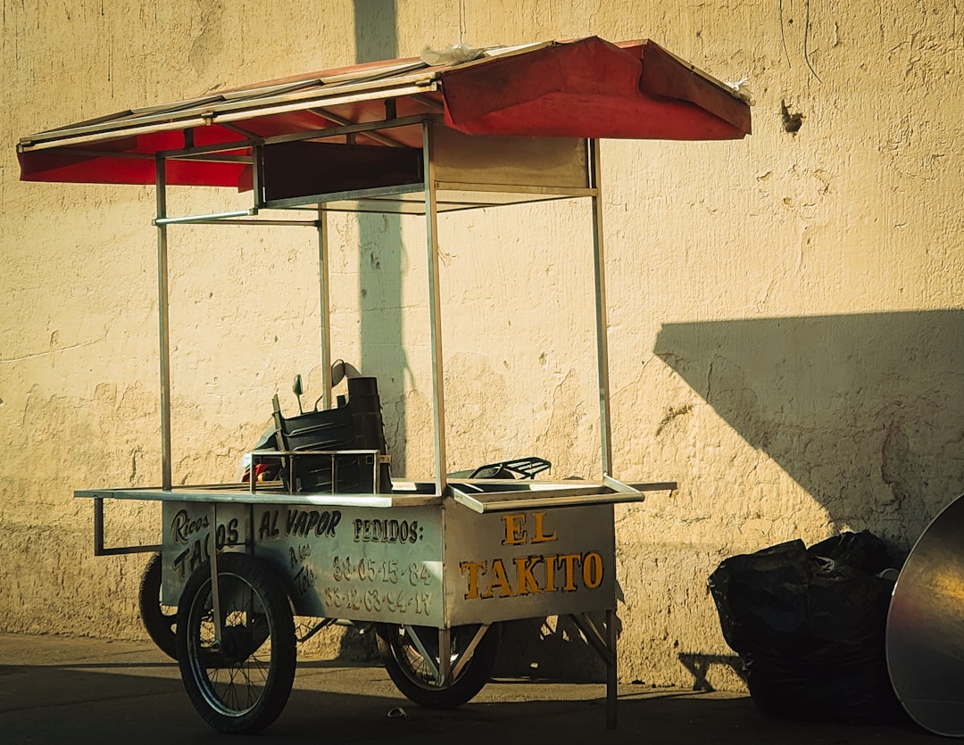 A street food cart sits by a wall.