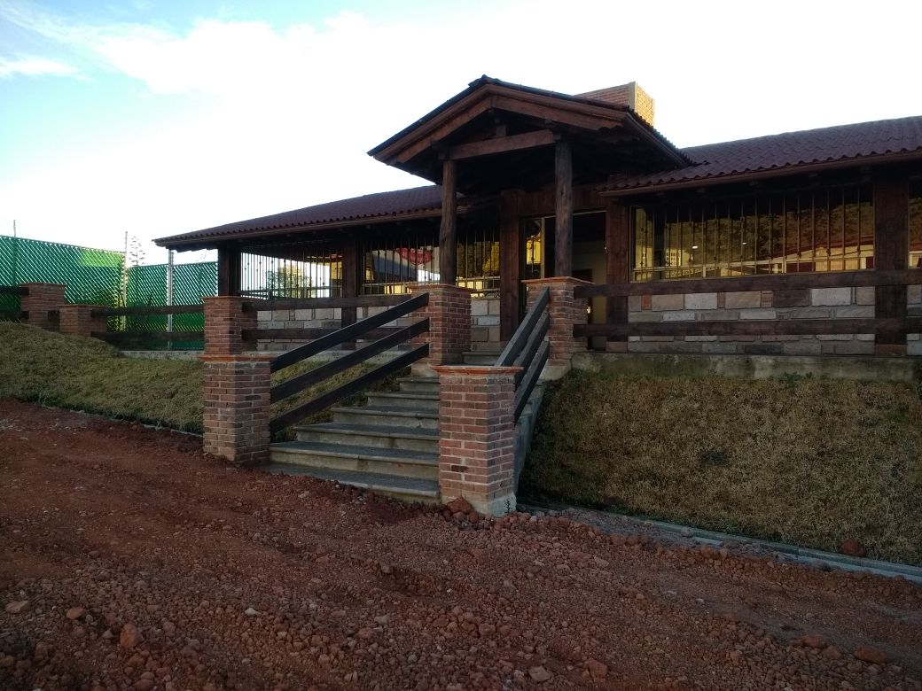 Exterior de Chiquihuitito Restaurante con su letrero rojo y una mesa al aire libre, mostrando una bandeja de enchiladas y una jarra de cerveza