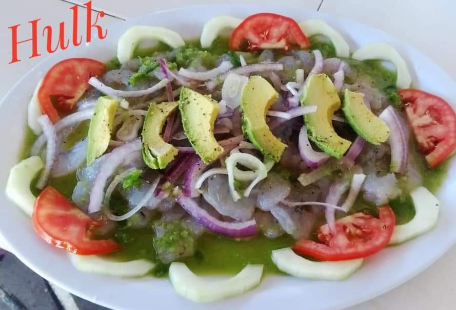 Ceviche servido en Mariscos El Chicole con rodajas de limón y michelada al fondo