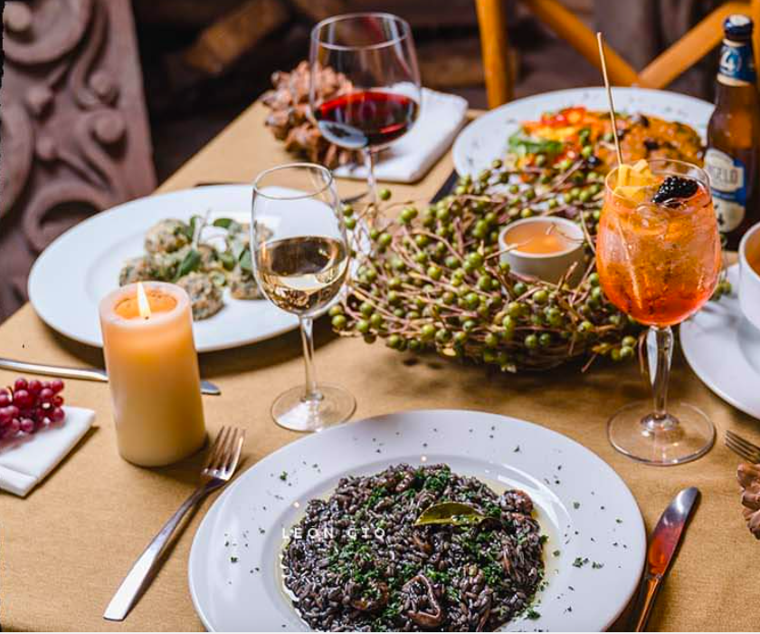 Interior de Peperonata con mesas de madera, cocineros en acción y clientes disfrutando de platos recién preparados