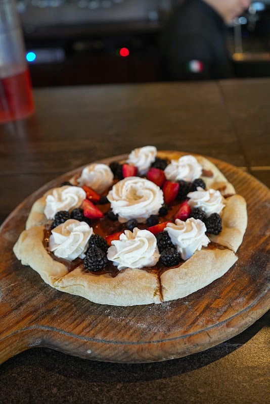 Exterior de Peperonata en Blvd. Campestre 1101, mostrando su fachada moderna y una mesa con una pizza de cuatro quesos y tiramisú al fondo