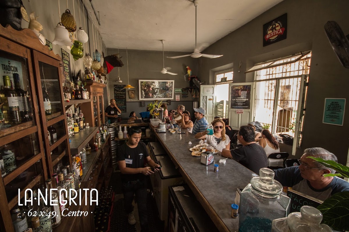 Monk Sportsbar interior with large TV screens, neon lights, and a bartender mixing a mezcal‑smoked Old Fashioned