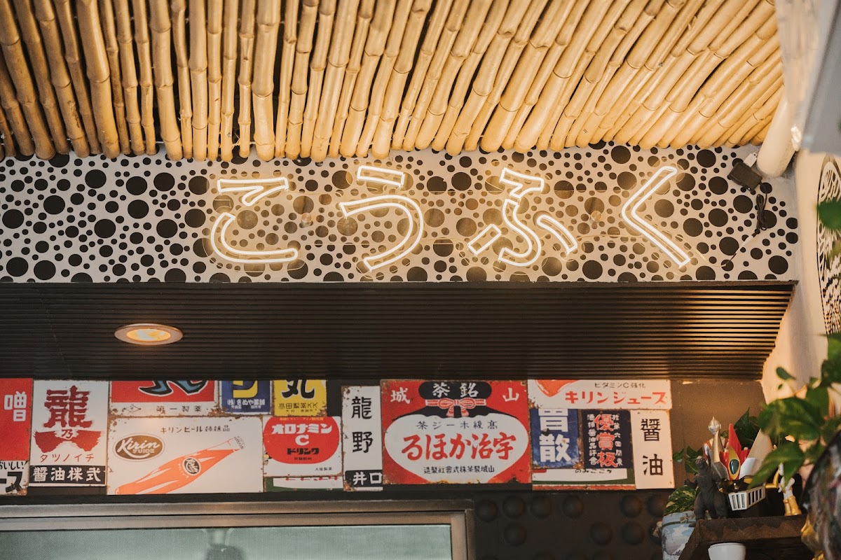 Interior de Kōfuku, barra de sushi con chefs preparando rolls, luces cálidas y ambiente acogedor