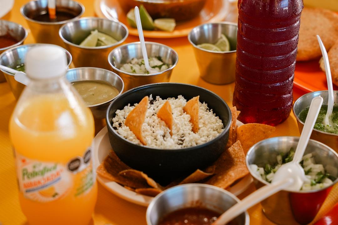 Fachada colorida de La Casa de Lalo en la calle 13, con letrero de neón y clientes en la fila al amanecer
