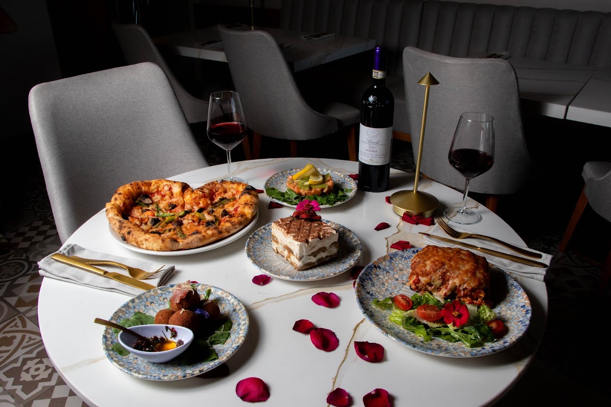 A golden 4 cheese pizza with bubbling crust and vibrant basil, served on a white plate