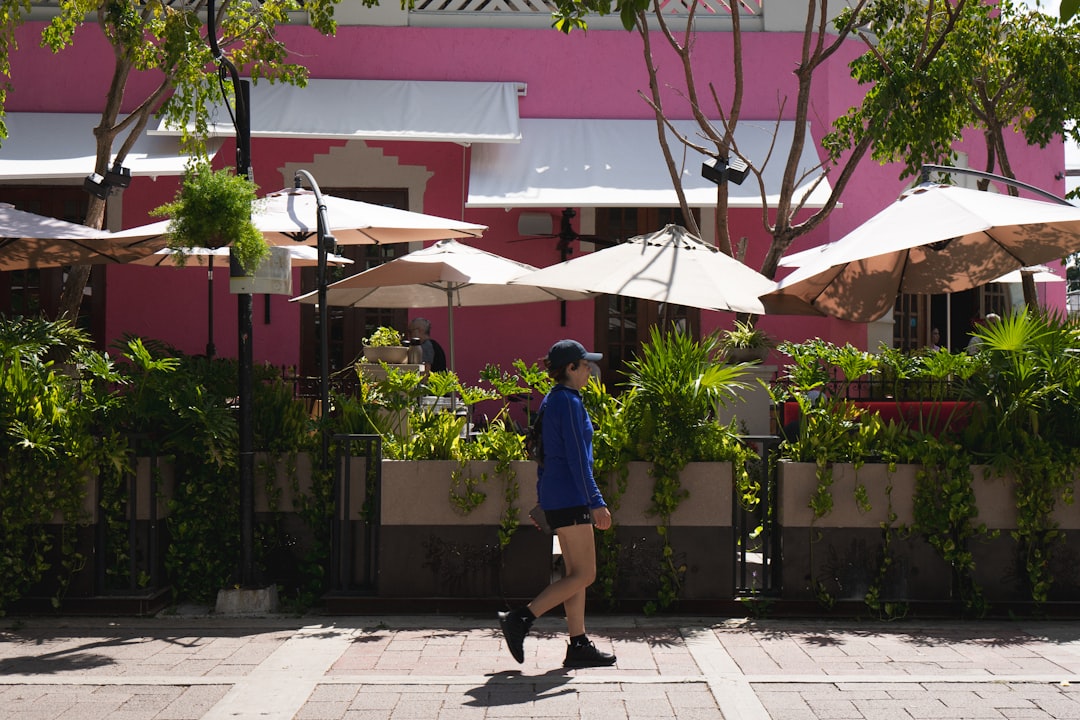 A person walks past a pink building.