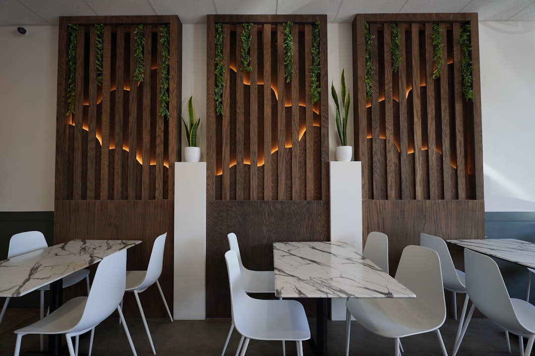 A restaurant with tables and white chairs and wooden screens