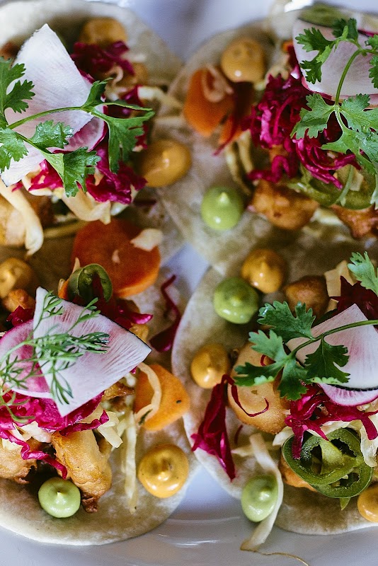 Taco de carnitas y cerveza artesanal en Plaza Modelo, mostrados en una mesa exterior