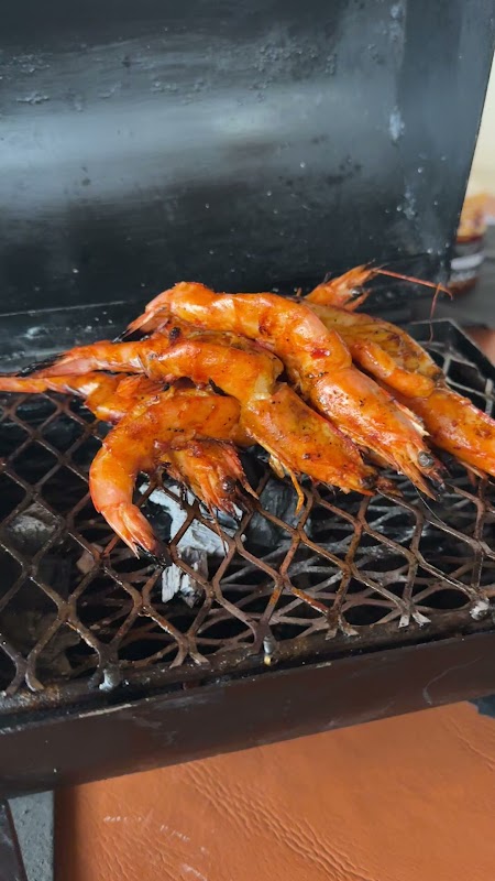 Patmos Cocina de Mar's waterfront patio at sunset, tables set with grilled octopus and a glass of white wine — close-up of the dish and ambience