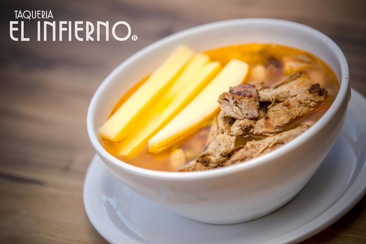Close‑up of the steaming chicken tinga canasta at Tacos De Canasta Canastu, basket on a wooden table