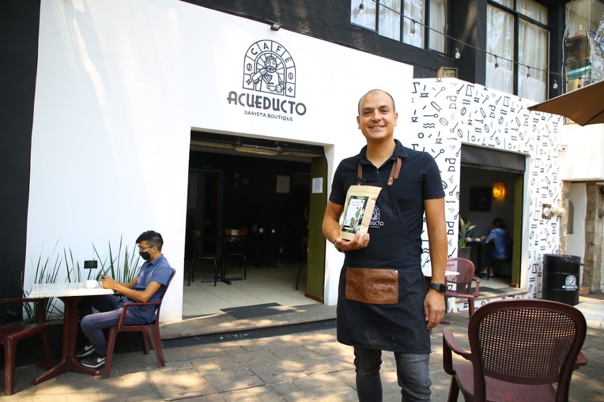 FIKA COFFEE SHOP storefront on Ignacio Zaragoza with a barista preparing a flat white, morning light flooding the interior