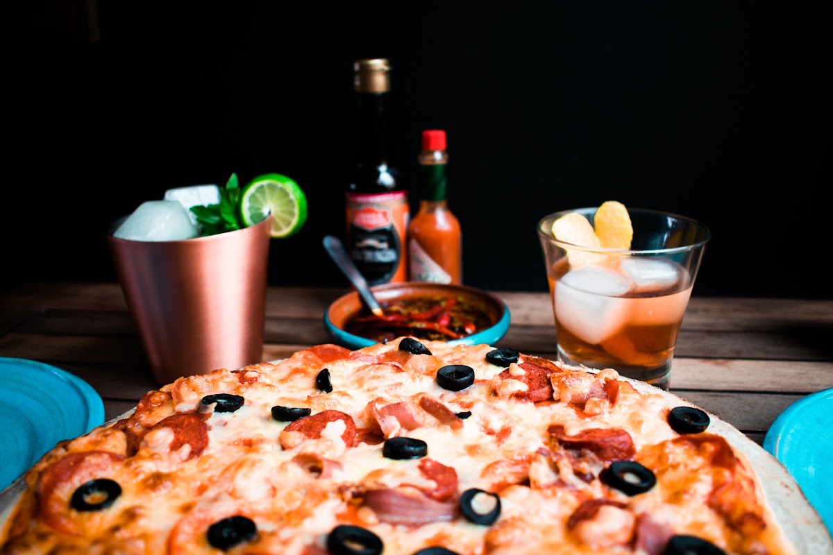 Little Caesars Camelinas mostrando la caja de pizza recién salida del horno, con queso derretido y borde crujiente, frente al mostrador del local