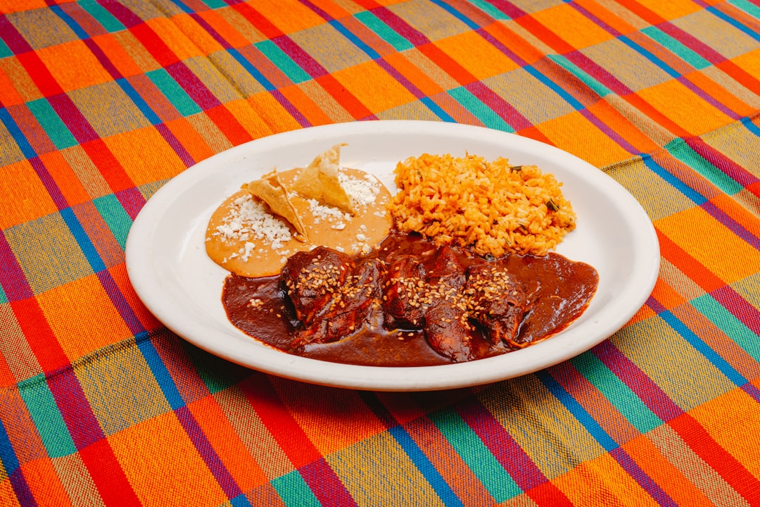 A white plate topped with meat and rice