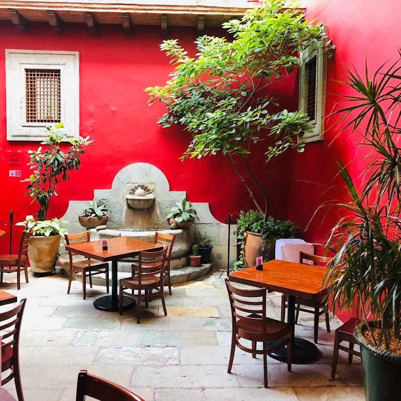 Comedor de Catedral Restaurant con mesas de madera y una porción de mole oaxaqueño junto a un vaso de tejate