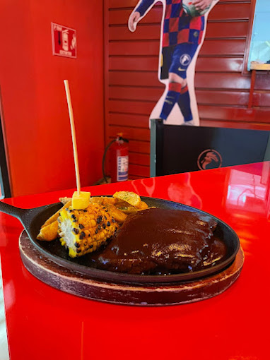 Espacio Luvina – tlayuda crujiente en plato de madera, rodeada de plantas del patio