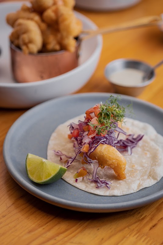 Marisquería Playa del Carmen's patio with a plate of grilled shrimp and a glass of mezcal