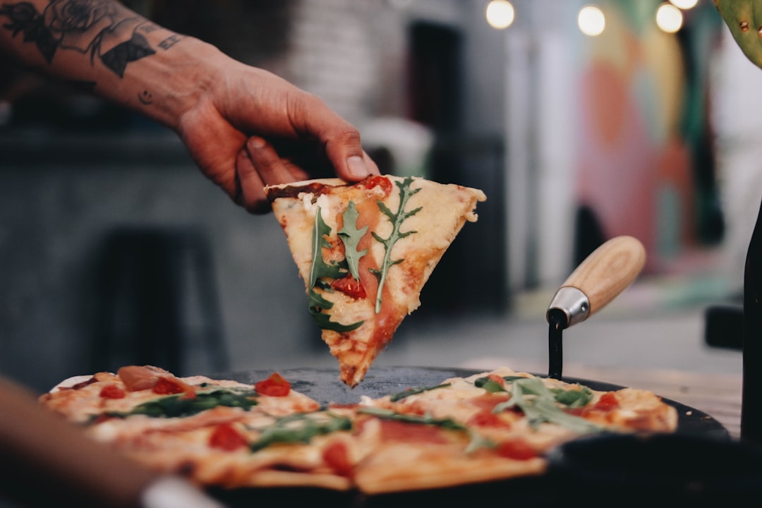 a person taking a slice of pizza from a pan