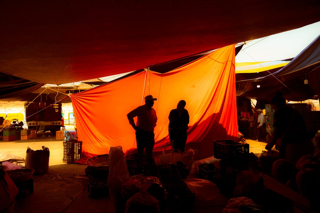 People stand under a large orange tent.