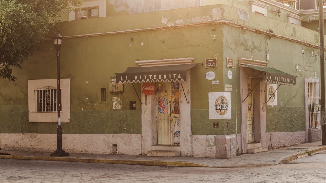 a green building with a white door on a street corner