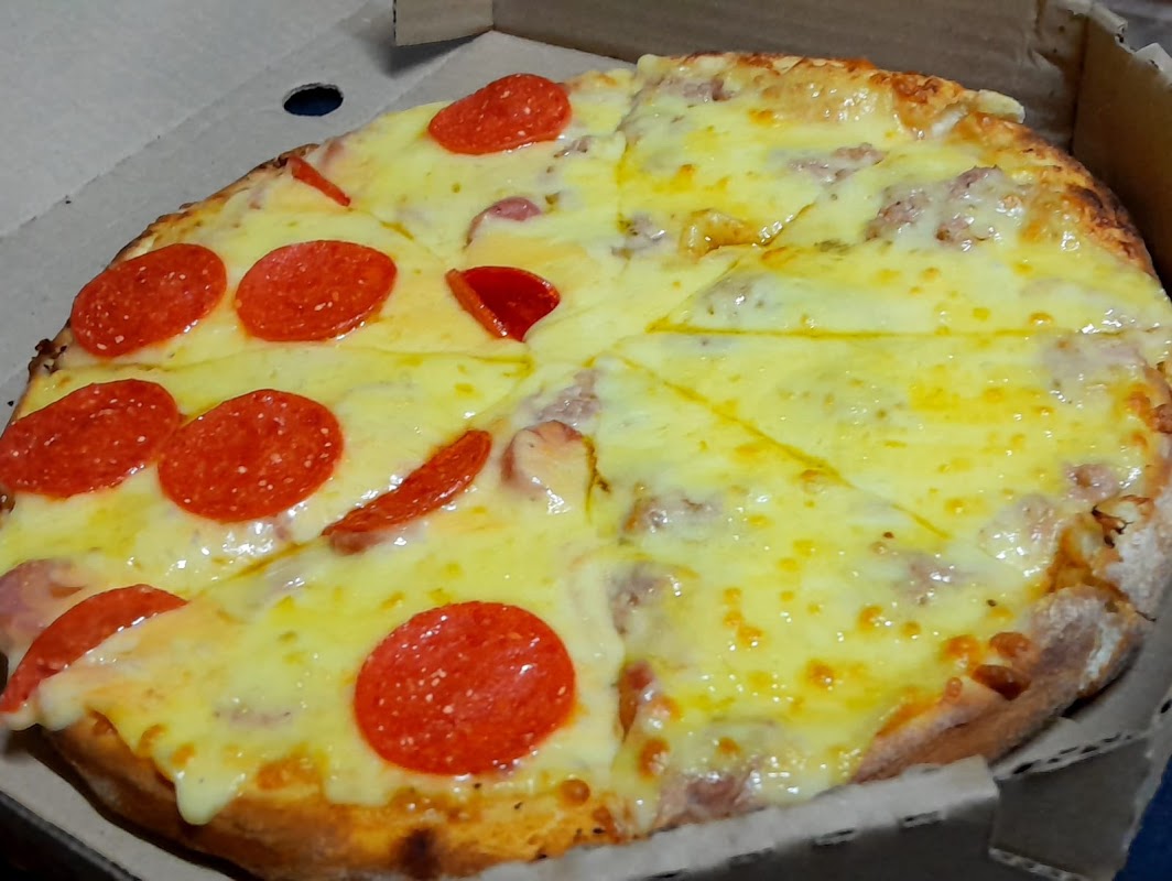 PIZZERIA VATOS LOCOS con su pizza de pepperoni crujiente, foco en la caja de entrega y el chef en la cocina