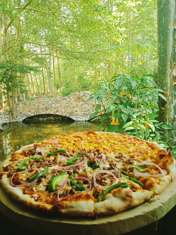 El chante – imagen del exterior rodeado de árboles y la pizza de trucha en primer plano, mostrando la frescura del pescado