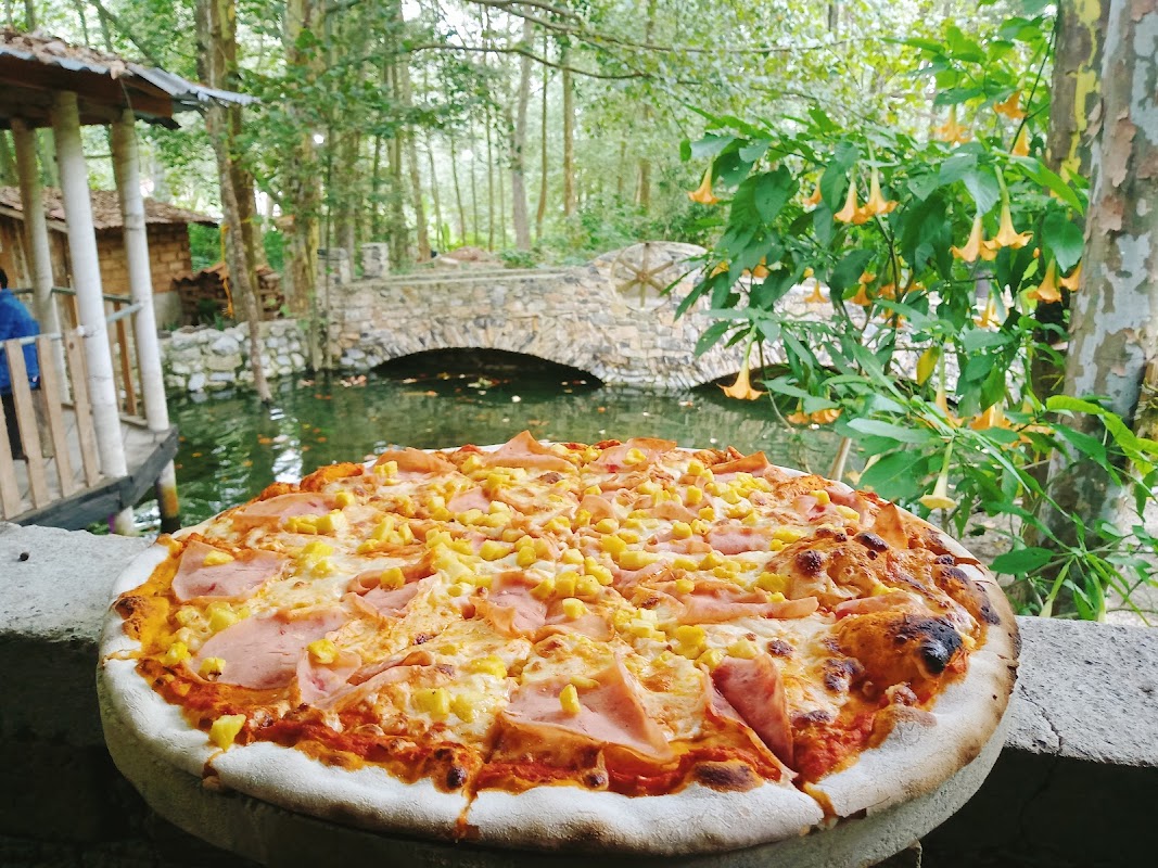 Pizzería Vatos Locos – foto del interior con horno de leña y una pizza margarita recién salida, mostrando la masa inflada y el queso fundido