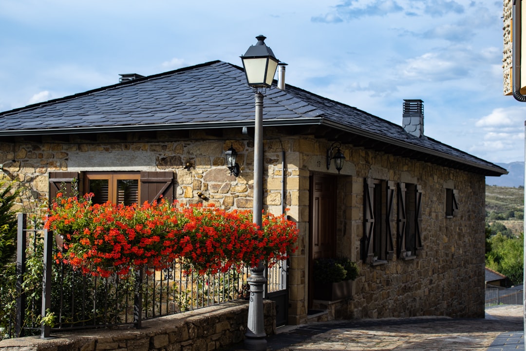 a stone building with red flowers in front of it