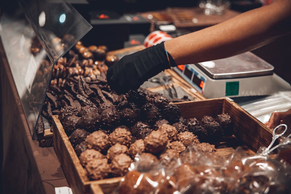 Hand picking delicious chocolates in a shop display with variety.