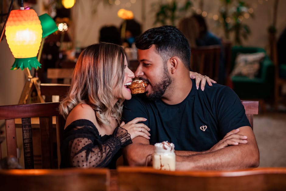 A joyful couple shares a dessert in a cozy cafe setting, highlighting togetherness and romance.