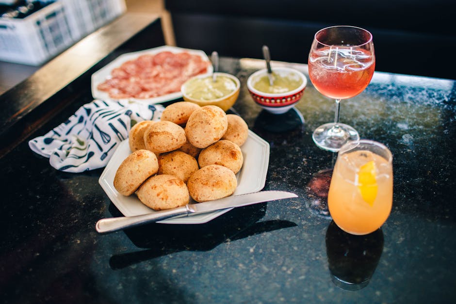 Black bar counter with plate of aromatic buns and assorted sauces with pair of cocktails