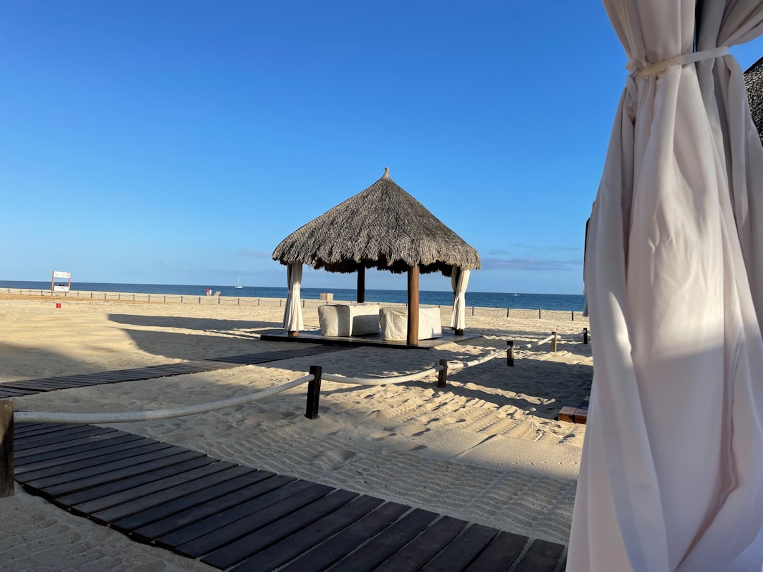 a gazebo sitting on top of a sandy beach next to the ocean