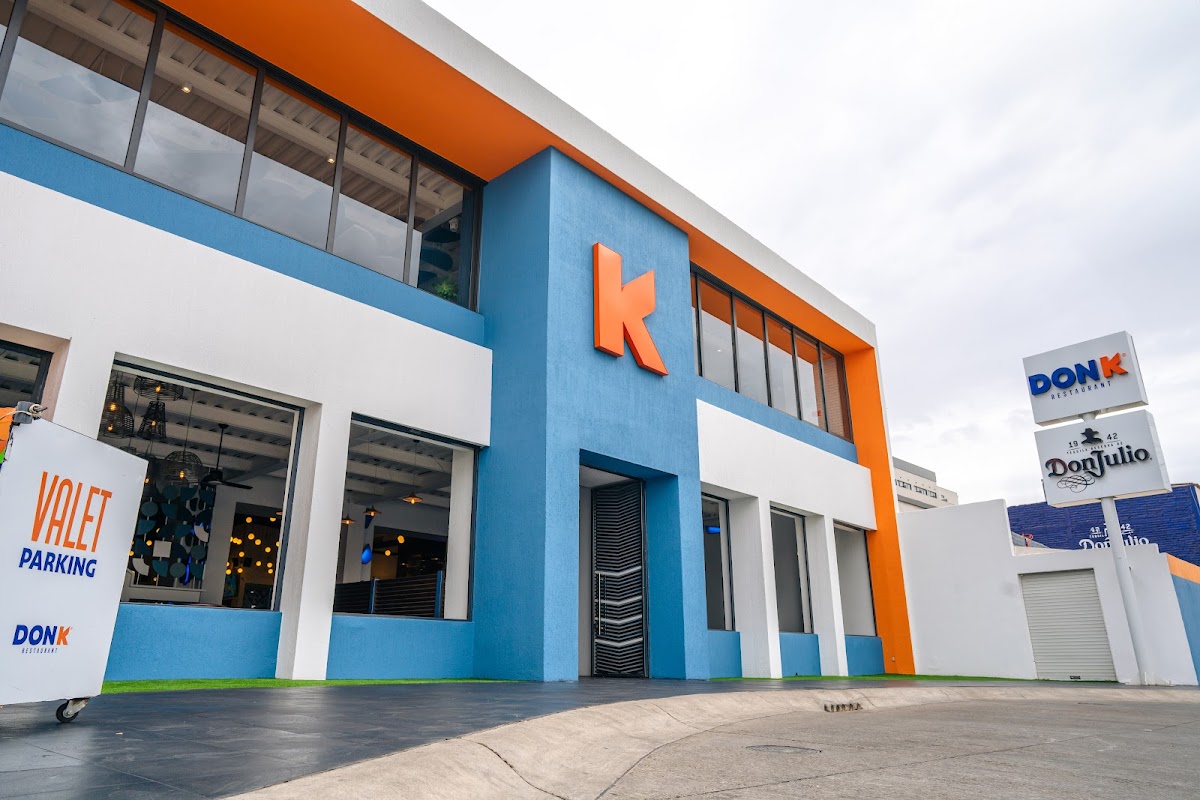 Exterior de Don K Restaurant en Av. Dr. José Ricardo Alcalá Íñiguez, mostrando el patio de madera y el bar, con un plato de pulpo a la parrilla en primer plano