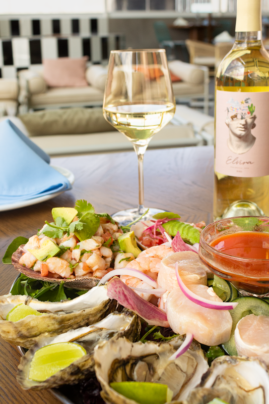Villa Marina Península’s waterfront patio with a plate of grilled shrimp al ajillo and a glass of chilled white wine — sunset view