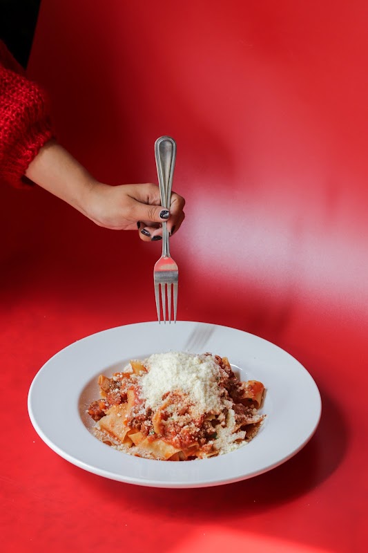 Primer plano de la pasta fresca en Quattro Fogon Italiano, con salsa de tomate brillante y parmesano rallado, servido en plato blanco