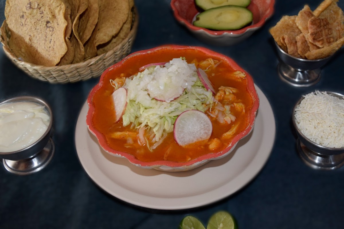 Tazón humeante de pozole rojo en La Casa del Rico Pozole (nueva sucursal), con maíz, carne y salsa