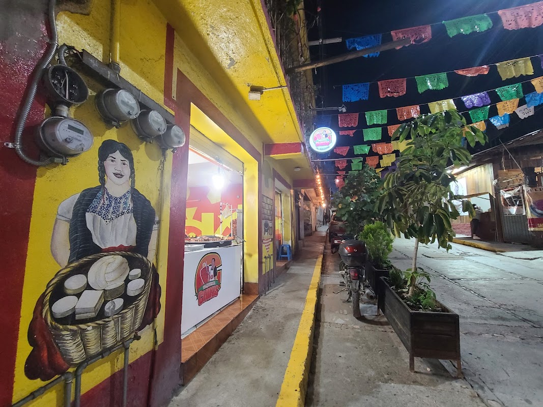 Exterior de Los Sauces con mesas al aire libre y parrilla encendida, mostrando el letrero del restaurante