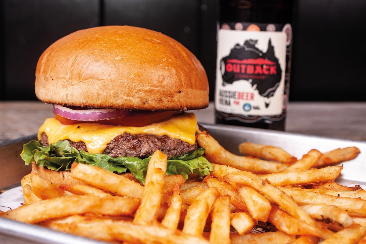 Bear And Wolf Burger & Dogo Gourmet — close‑up of a gourmet burger with melted cheese, bear honey drizzle, and boneless wings on the patio